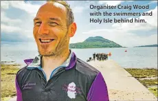  ??  ?? Organiser Craig Wood with the swimmers and Holy Isle behind him.