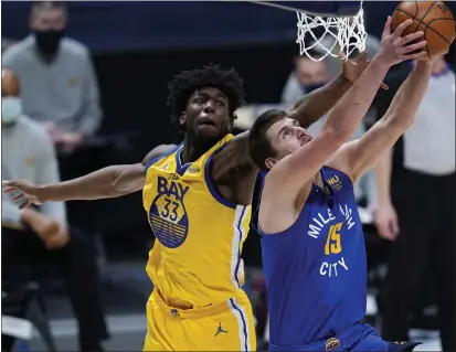  ?? PHOTOS BY DAVID ZALUBOWSKI — THE ASSOCIATED PRESS ?? Nuggets center Nikola Jokic, front, drives to the rim for a reverse dunk past Warriors center James Wiseman in the first half on Thursday.