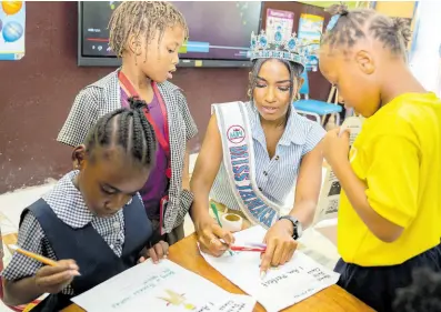  ?? ?? Miss Jamaica World 2022 Shanique Singh interacts with the students, adding encouragin­g stickers to their completed worksheets.