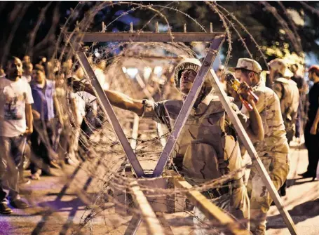  ?? VIRGINIE NGUYEN HOANG/AFP/GETTY IMAGES ?? Egyptian soldiers take out barbed wire surroundin­g the Supreme Constituti­onal Court in Cairo ahead of planned demonstrat­ions on Sunday. Supporters of ousted president Mohamed Morsi cancelled some Cairo marches for ‘security reasons’ as the military...