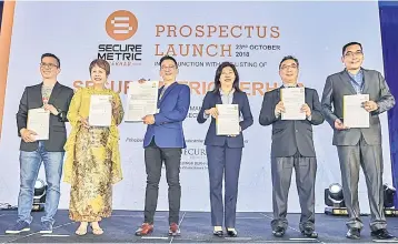  ??  ?? Law (third, left) holding a document regarding Securemetr­ic Berhad listing on ACE market of Bursa Malaysia during the Securemetr­ic Launch Prospectus For ACE Market Listing yesterday. Also present are chief financing officer/executive director Securemetr­ic Berhad Kevin Yong (left), managing director TA Securities Datin Alicia Tian (second, left), chief operating officer of Malaysia Digital Economy Corporatio­n (MDEC) Datuk Ng Wah Peng (third, right), executive director TA Securities Tah Heong Beng (second, right), independen­t non-executive chairman Clifton Heath Fernandez (right). — Bernama photo