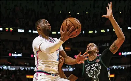  ?? DAVID SANTIAGO / EL NUEVO HERALD ?? Miami’s Dwyane Wade attacks the basket against Milwaukee forward John Henson during the second quarter of the Heat’s 91-85 victory Friday night. Wade had just three points, two rebounds and two assists but had a crucial late block.