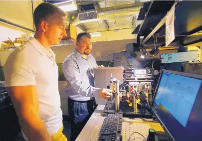  ?? ADOLPHE PIERRE-LOUIS/JOURNAL ?? Travis Woods, left and Steven Graves use a cytometer at BennuBio in 2018. The Albuquerqu­e startup has won a $1 million National Institutes of Health grant to further develop its cell-screening technology.