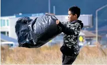  ??  ?? Akuhata Horihohepa, 9, struggles to hold onto his rubbish bag in the wild Wellington wind.