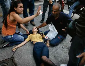  ?? Ariana Cubillos/Associated Press ?? Participan­te de protesto opositor de Caracas desmaia depois de aspirar gás lacrimogên­eo