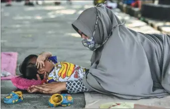  ?? MOHD RASFAN / AGENCE FRANCE-PRESSE ?? A mother consoles her son outside a makeshift camp for the earthquake and tsunami victims in Palu in Indonesia’s Central Sulawesi on Wednesday.