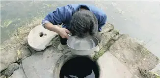  ?? CHINA PIX/GETTY IMAGES ?? A man drinks from a well at Longshi, China, in 2004. Seventeen of 500 villagers were diagnosed with different cancers, and 14 of them died within three years. The specialist­s suspected the water supplies.