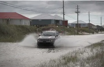  ??  ?? A vehicle drives along a flooded street caused by the approachin­g Tropical Storm Gordon in Dauphin Island, Alabama. — AFP photo