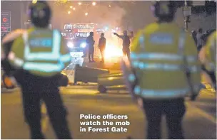  ??  ?? Police officers watch the mob in Forest Gate