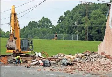  ?? Photos by John Bailey ?? Above: A woman walks her dog along the levee Wednesday morning as a crew from Ecker Constructi­on begins to demolish the American Legion Post 5 building on Shorter Avenue. Left: Placards with the words “veterans,” “youth,” “defense” and “Americanis­m” sit atop columns on the front of the American Legion building. Below: It’s expected to take several days to clear the rubble from the demolition site on Shorter Avenue.