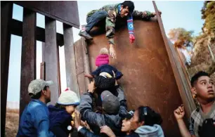  ?? Photo: Alkis Konstantin­idis/Reuters ?? Honduran migrants, who are part of a caravan of thousands from Central America, try to climb over a border fence to cross illegally from Tijuana, Mexico to the US yesterday