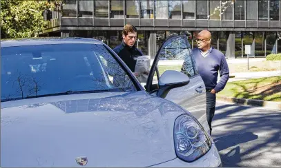  ?? REANN HUBER / REANN.HUBER@AJC.COM ?? Todd Duncan (right), a senior editor at The Atlanta Journal-Constituti­on, has a 2018 Porsche Cayenne GTS delivered to him at The Atlanta Journal-Constituti­on office. This car is part of Porsche’s car subscripti­on service.