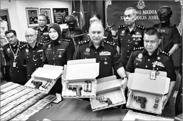  ??  ?? Mohd Mokhtar (front, second right) shows the weapons seized by the police during a press conference. — Bernama photo