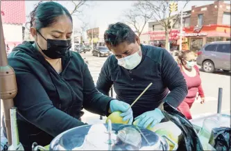  ?? Associated Press ?? Ruth Palacios and Arturo Xelo, a married couple from Mexico, work at their fruit stand in the Corona neighborho­od of the Queens borough of New York on April 13. They worked seven days a week for months disinfecti­ng COVID-19 patient rooms at the Memorial Sloan Kettering Cancer Center in New York City, but weren't paid overtime, Palacios says. The couple filed a federal lawsuit against the contractor that hired them, alleging their pay was cut without their knowledge from $15 an hour to $12.25. They’re now selling fruit to make ends meet.