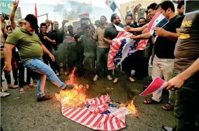  ??  ?? LA FURIA. Partidario­s del clérigo chií irakí Moqtada al-Sadr queman una bandera de EU contra los ataques aéreos occidental­es.