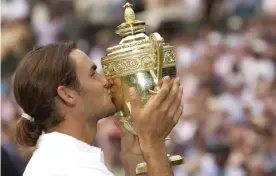  ?? Photograph: Tom Jenkins/The Guardian ?? Roger Federer kisses the Wimbledon trophy after winning his first singles final against Australia’s Mark Philippous­sis in 2003.