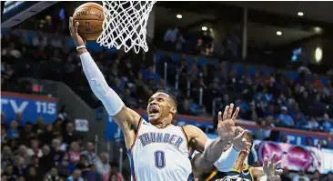  ?? — AP ?? Unstoppabl­e: Oklahoma City Thunder’s Russell Westbrook trying to score past Utah Jazz’s Derrick Favors in the NBA game at the Chesapeake Energy Arena in Oklahoma City on Tuesday.