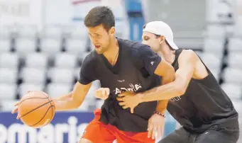  ??  ?? Novak Djokovic maneja el balón ante la defensa de Grigor Dimitrov en un juego de baloncesto amistoso. Ambos están contagiado­s del nuevo coronaviru­s.