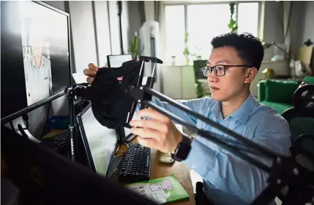  ?? — AFP ?? Mr Fix It: Wenda’s agony aunt Gu setting up a teleprompt­er and camera by his computer at his home in Beijing.