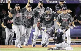  ?? CHARLIE RIEDEL / AP ?? Indians teammates prepare to mob kneeling first baseman Carlos Santana after his final catch in the ALCS clincher against the Blue Jays on Wednesday.