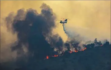  ?? I rfan Khan Los Angeles Times ?? A CHINOOK HELICOPTER makes a water drop Tuesday on the Blue Ridge f ire. The blaze erupted on Monday in the Santa Ana Canyon, a notorious wind tunnel, and spread quickly west toward Yorba Linda.