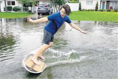  ?? JOECAVARET­TA/SOUTHFLORI­DASUNSENTI­NEL ?? Dominic Luckett rides a skimboard on Northeast SecondAven­ue inOakland Park on Sunday. South Floridawas under a floodwatch and flood advisory Sunday because of heavy rainfall.