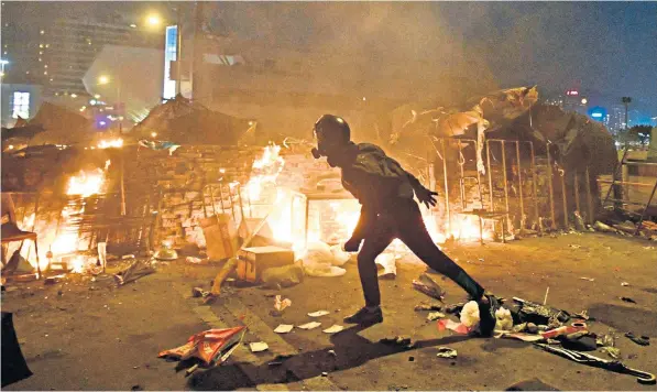  ??  ?? Above, protesters build a fire outside the Polytechni­c University, and clash with police above Crossharbo­ur Tunnel, left. They used bows and arrows and Molotov cocktails, far left. Left, the officer injured by an arrow in his leg