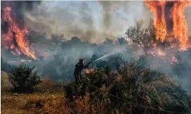  ?? Photograph: Valérie Gache/AFP/Getty Images ?? A firefighte­r douses flames on a wildfire at the Panorama settlement near Agioi Theodori, about 70km west of Athens, on 18 July 2023.