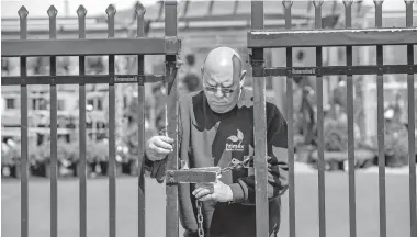  ?? [MICHAEL BRYANT/ THE PHILADELPH­IA INQUIRER/ TNS] ?? David Green, owner of the currently shut down Primex Garden Center in Glenside, Pa., relocks the gate March 24 after entering his business. He was forced to close as a nonessenti­al business in Pennsylvan­ia. He and a few remaining employees, mostly family, are still watering and maintainin­g plants, hoping they will be able to reopen.