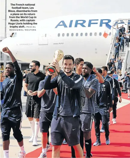  ?? /PASCAL ROSSIGNOL/ REUTERS ?? The French national football team, Les Bleus, disembarks from a plane on its return from the World Cup in Russia, with captain Hugo Lloris holding the trophy aloft.