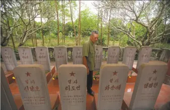  ?? Hau Dinh / Associated Press ?? War veteran and memorial caretaker Duong Van Dau walks among a row of headstones of North Korean pilots in Bac Giang province. The pilots died while fighting American bombers.