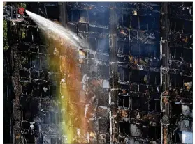  ?? ALASTAIR GRANT / ASSOCIATED PRESS ?? The sun creates a rainbow effect Wednesday as firefighte­rs work at the scene of a deadly fire in the Grenfell Tower high-rise in London. The 24-story block of apartments in the Kensington area was home to about 500 people.