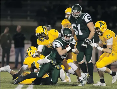  ?? GREG PENDER ?? Tyler Chow of the University of Saskatchew­an Huskies draws a crowd running the ball against the University of Alberta Golden Bears during CIS football action at Griffiths Stadium on Friday. The Huskies won the game 48-9 and are headed for the playoffs.