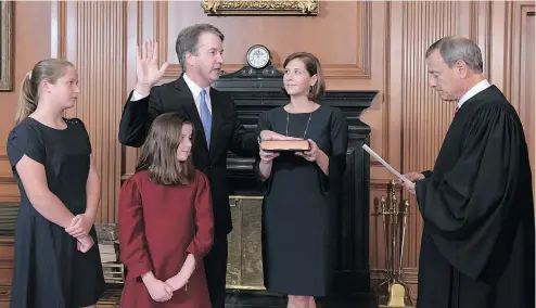  ?? — GETTY IMAGES ?? U.S. Supreme Court Chief Justice John Roberts administer­s the Constituti­onal Oath to Brett Kavanaugh Saturday in Washington as wife Ashley Kavanaugh holds the Bible and daughters Margaret and Liza look on.