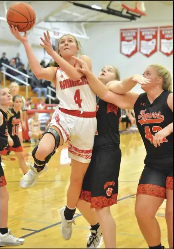  ?? Staff photo/ Jake Dowling ?? New Knoxville’s Avery Henschen drives through the lane and past a couple of Jackson Center defenders in the third quarter of a non- conference girls basketball game against the Tigers on Tuesday.