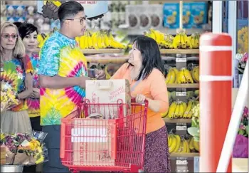  ?? Irfan Khan Los Angeles Times ?? TRADER JOE’S employees, wearing tie-dye T-shirts in memory of slain co-worker Melyda Corado, greet customers as they reopen on Thursday, almost two weeks after a fatal shootout at the Silver Lake store.