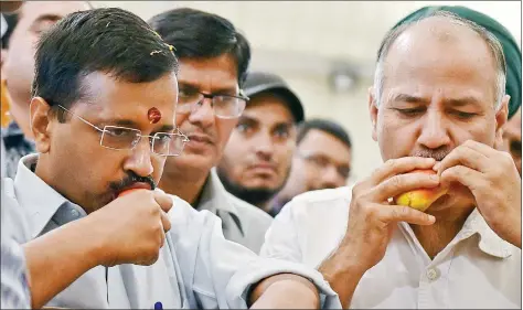  ?? PTI ?? Delhi Chief Minister Arvind Kejriwal and Deputy CM Manish Sisodia eat mangoes at the Annual Mango Festival at Janakpuri Dilli Haat in New Delhi on Friday.