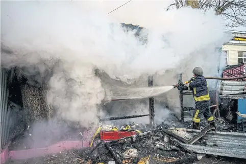  ?? AFP ?? A rescuer extinguish­es a fire in a burning shop after Russian shelling to Ukrainian city of Kherson on Saturday.
