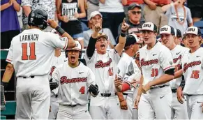  ?? Nati Harnik / Associated Press ?? Oregon State designated hitter Trevor Larnach, left, is greeted by teammates after he scored the go-ahead run against Cal State Fullerton in the eighth inning of Saturday’s College World Series opener.