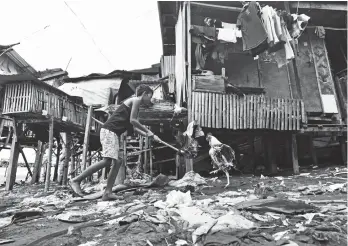  ?? JULIET C. REVITA ?? LIFE GOES ON. A young boy trains a fowl to fight using a dummy. Around him and as far as the eyes can see is garbage strewn all over.