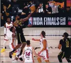  ?? MARK J. TERRILL — AP ?? Lakers forward LeBron James (23) goes up for a shot between the Heat’s Jimmy Butler, center left, Tyler Herro (14), and Kelly Olynyk
(9) during the second half of Game 2 of the NBA Finals on Friday in Lake Buena Vista, Fla.