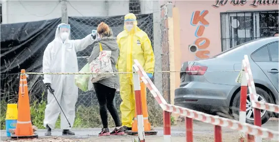  ??  ?? Controles. Personal sanitario le toma la temperatur­a a una mujer en el ingreso a un barrio de Tigre que fue foco de contagios, la semana pasada.