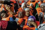  ??  ?? Migrants aboard a rubber dinghy off the Libyan coast receive aid Saturday from rescuers aboard the Open Arms boat. Sixty were rescued as Italy’s right-wing interior minister rejected accepting them.