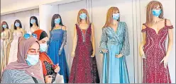  ?? AFP ?? ■
Women exit a garment shop where masks are placed on mannequins, in the West Bank city of Hebron.