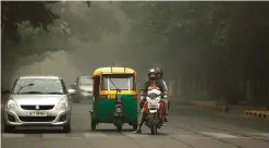  ??  ?? NEW DELHI: A family on a motorcycle wait at a crossing amidst smoke and smog.