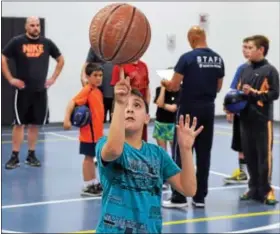  ??  ?? Frank Nesci, 9, spins a ball on his finger as teams are picked for the North Penn Police Athletic League basketball tournament at the Lansdale Area Family YMCA.