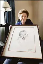  ?? CHRIS O'MEARA / Associated Press ?? Ann Turner Cook, poses at her Tampa, Fla., home Wednesday afternoon Feb. 4, 2004, with a copy of her photo that is used on all Gerber baby food products. Ann Turner Cook, whose cherubic baby face was known the world over as the original Gerber baby, has died. She was 95. Gerber announced Cook's passing in an Instagram post on Friday, June 3.