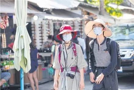  ?? NATTHAWAT WICHEANBUT ?? Foreign tourists wear masks to protect themselves against Covid-19 at Bangkok’s Chatuchak market.