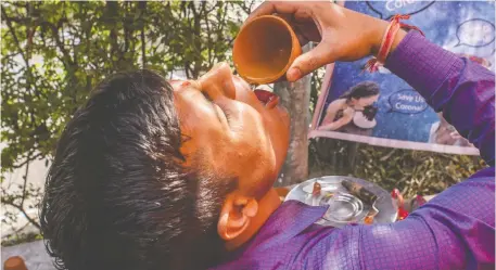  ?? YAWAR NAZIR/GETTY IMAGES ?? A member of the Akhil Bharat Hindu Mahasabha group drinks cow urine as a potential method of warding off COVID-19.