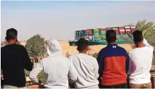  ?? ISLAM SAFWAT/BLOOMBERG ?? Spectators watch as the Ever Given container ship moves along the Suez Canal toward Ismailia after being freed from the canal bank in Suez, Egypt, on Monday.